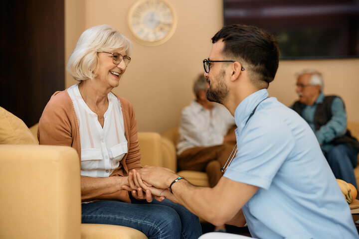 carer kneeling down and speaking to resident