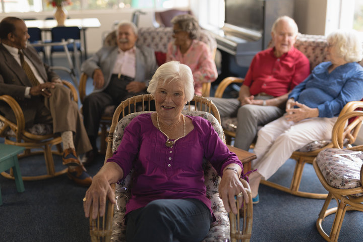 senior woman smiling in a care home sat with others
