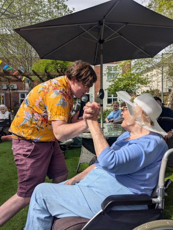 entertainer at care home singing to a resident in the garden