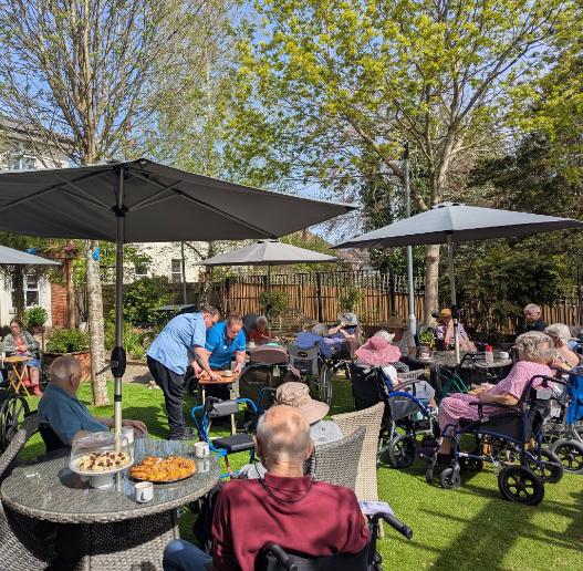 residents and staff in the garden at care home in sunshine