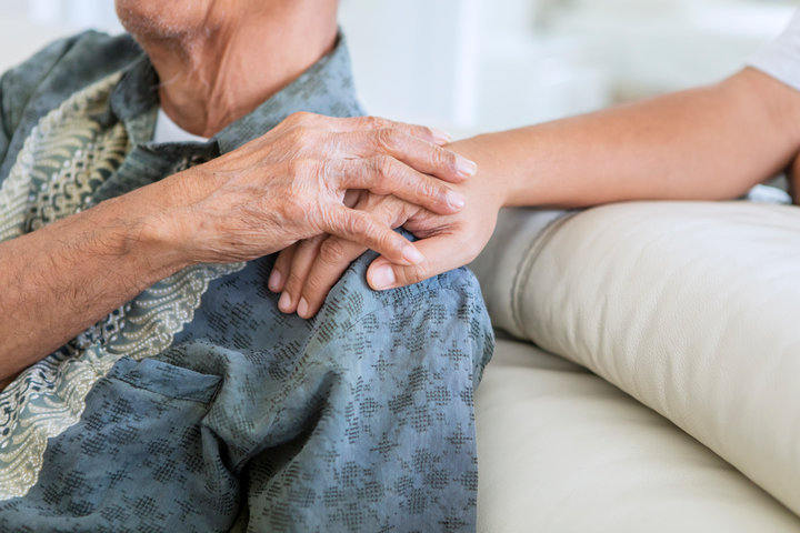 resident in end of life care with nurse hand on shoulder