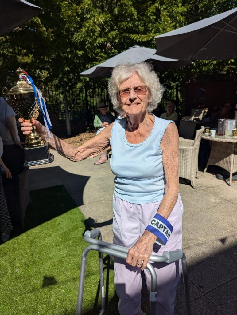 resident in a blue top holding a gold winners cup